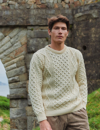 Die Aufnahme zeigt den Wollstrickpullover auf einem Herrenmodell in einer Landschaft in Irland.