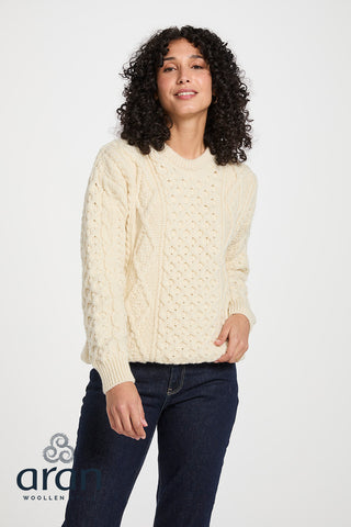 Der Wollpullover ist in einem klassischen Aran Zopfstrickmuster von vorne abgebildet.