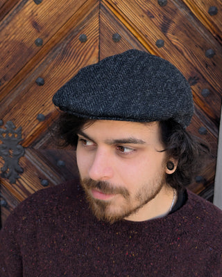 Zu sehen ist eine Schiebemütze aus Harris Tweed in Schwarzgrau, diese Mal von der anderen Seite.