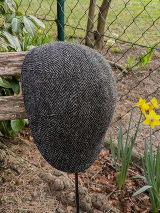 Die Ansicht zeigt das klassische Fischgrätmuster in dunkelgrau mit hellgrau als Harris Tweed Kappe. Insgesamt ein anthrazit Farbton.