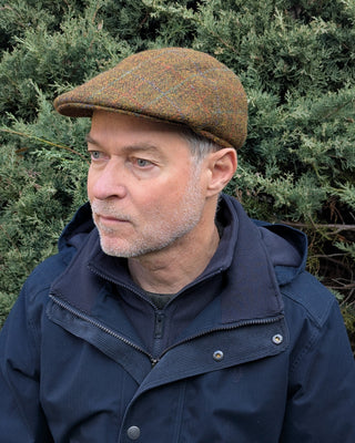Die Schiebermütze aus original Harris Tweed in rostbraunen Herbsttönen. Die Kappe ist getragen und in Dreiviertelansicht zu sehen.