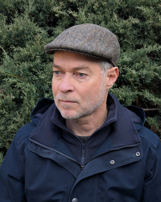 Dreiviertelansicht der Schiebermütze aus Harris Tweed in olivgrün.