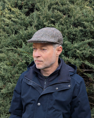 Zu sehen ist eine Schiebermütze aus Harris Tweed in beige grauer Farbstellung