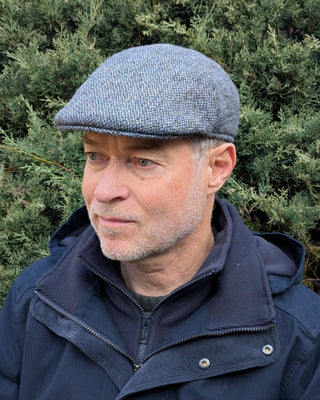 Zu sehen ist eine Schiebermütze aus Harris Tweed in Hellblau als Grundton.