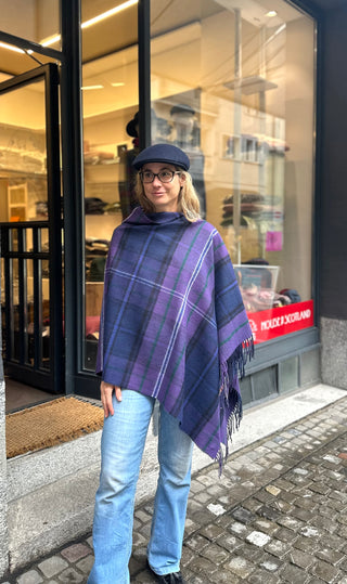 Der Tartan Poncho ist schräg über die Schulter getragen.