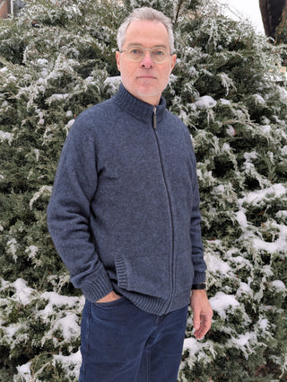 Die Strickweste ist in Dreiviertelansicht abgebildet. Der Kragen ist hochgeschlossen. Die beiden Taschen sind dezent eingearbeitet, sodass sie im Design nicht stören. 