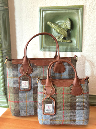 Zwei Harris Tweed Modelle im Größenvergleich: vorne die kleinere Mini Tote, hinten die größere Tote. Beide sind im hochwertigen Harris Tweed, highland check, in Kombination mit cognacfarbenen Leder ausgeführt.