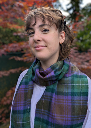 Zu sehen ist ein karierter Lammwollschal im Isle of Skye Tartan. Farbstellung Grüntöne, Violett und Braun.