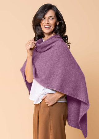 Zu sehen ist ein Strickcape in der Farbe Mauve. Das Cape ist mit der längeren Seite nach hinten getragen.