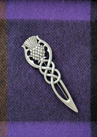 Zu sehen ist eine traditionelle schottische Kiltnadel (kilt pin) mit Distel und keltischem Flechtmotiv