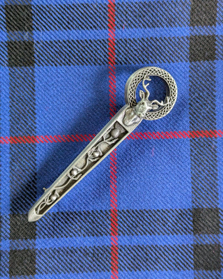 Zu sehen ist eine längliche Kiltnadel mit einem Hirschkopf und Disteln